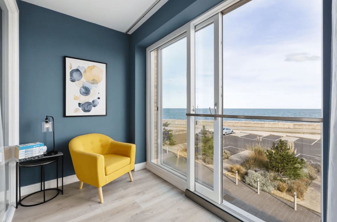 59 Campion Marina Village Greystones yellow arm chair in the glazed balcony area with view of the sea through glass sliding doors