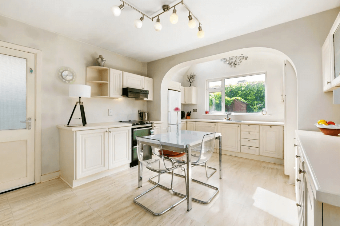 129 Wesbury Stillorgan Dublin Kitchen with white walls and ceiling, white-tiled flooring, cream-coloured cupboards, breakfast counter and medium-sized window to the rear garden