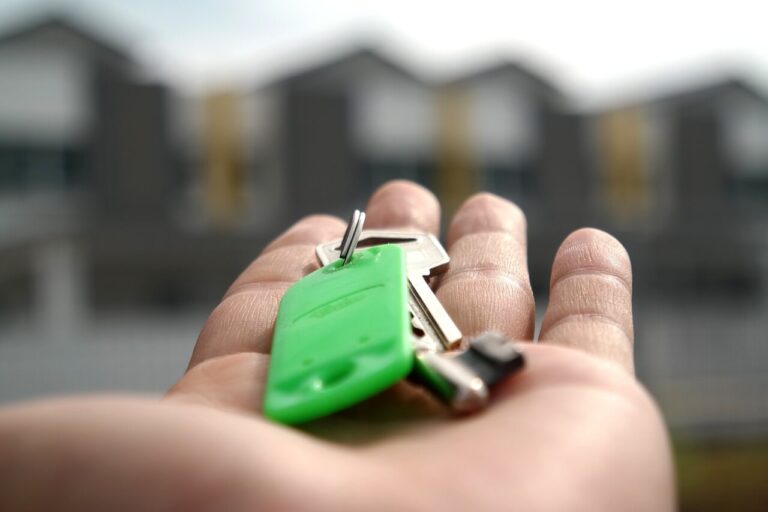 Lettings George and Maguire Properties with a hand holding keys to a property and houses blurred in the background