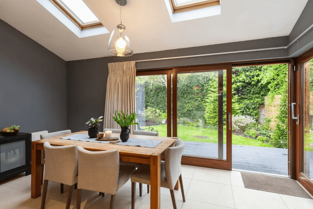 11 Glencairn Glade Leopardstown George and Maguire Properties dining room with large sliding doors to the rear garden and a large dining table with chairs on a white tiled floor