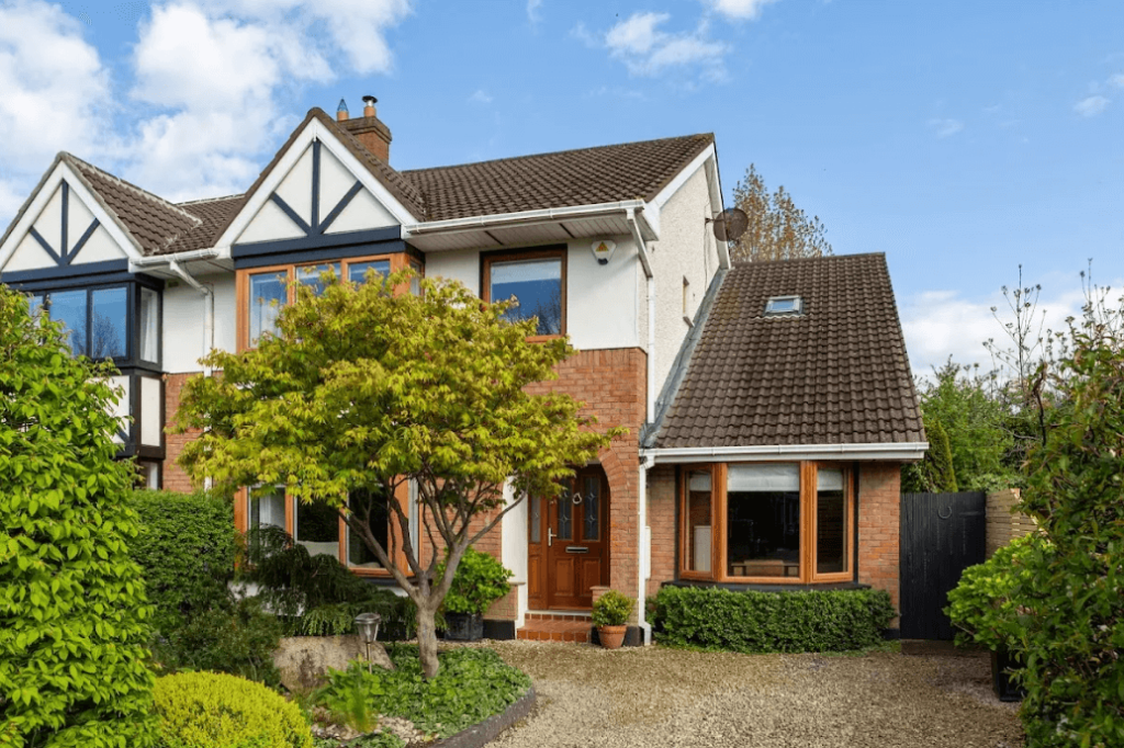 11 Glencairn Glade Leopardstown George and Maguire Properties front view of the house with a paved driveway, bushes and a small tree on a neat lawn