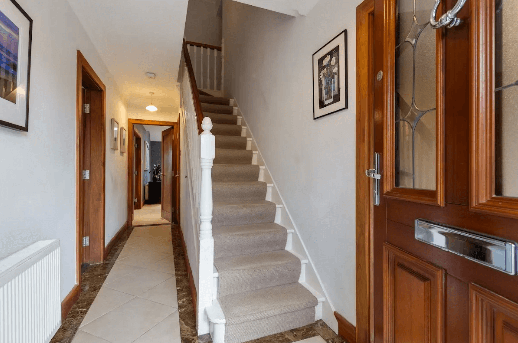 11 Glencairn Glade Leopardstown George and Maguire Properties hallway with carpeted stairs, dark timber flooring and entrance to kitchen