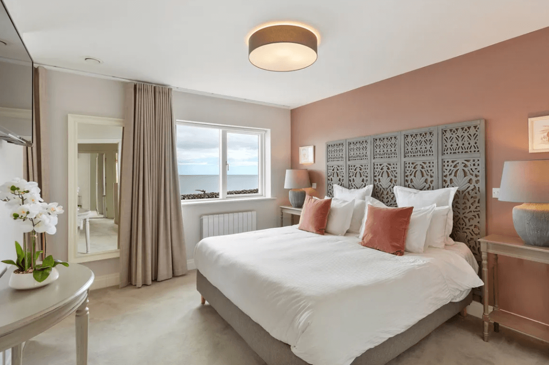 16 The Shore Greystones Wicklow George and Maguire Properties principal bedroom with large white bed, carpeted flooring and window with views of the Irish Sea