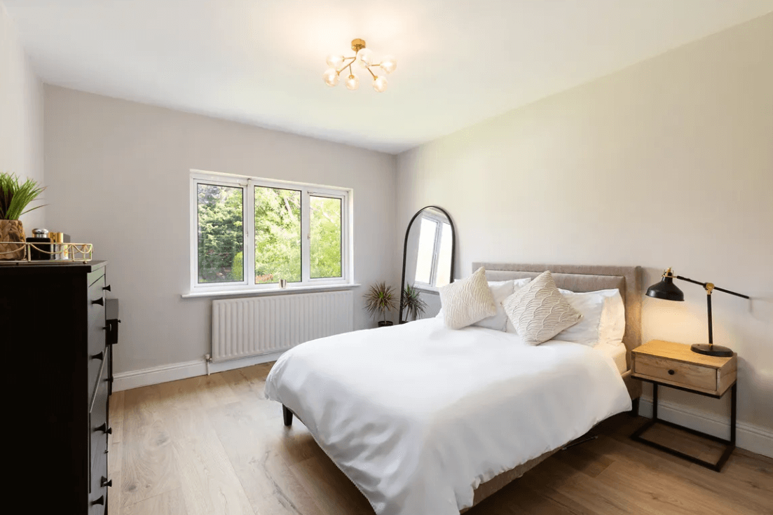 Balfour Ferndale Road Rathmichael Dublin George and Maguire Properties principal bedroom with large white bed, timber flooring, mirror and window with view outside