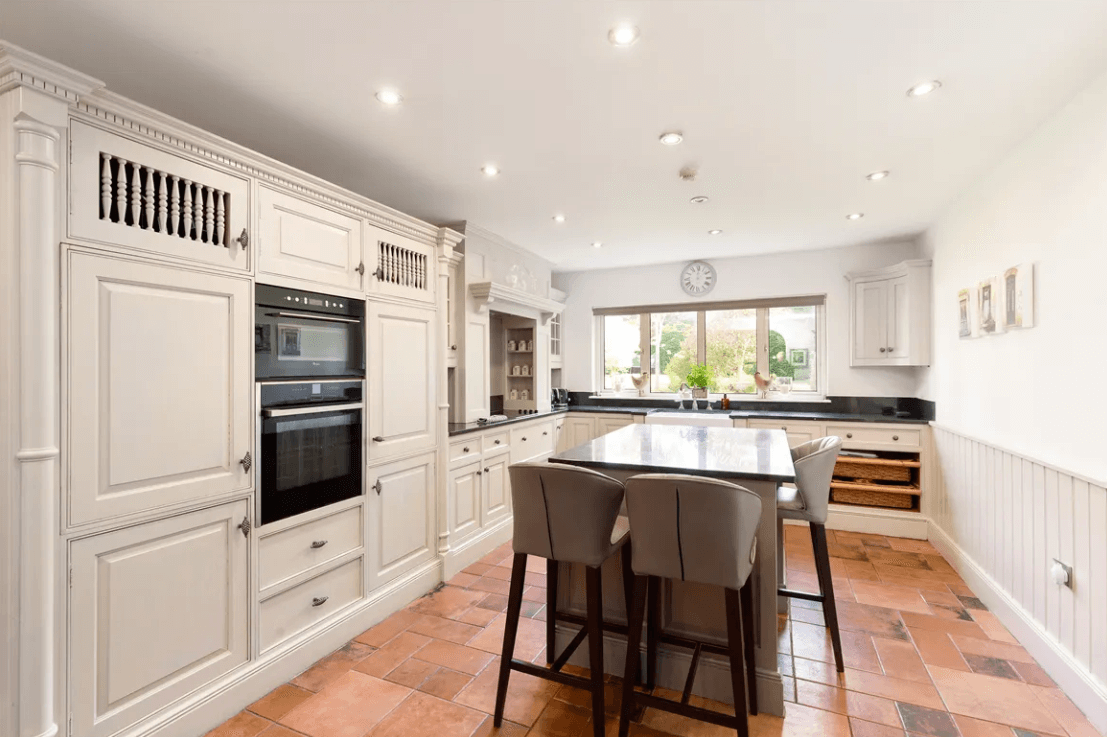 Balfour Ferndale Road Rathmichael Dublin George and Maguire Properties kitchen with tiled flooring, white cupboards, appliances, and island and a large window with a view to the rear garden