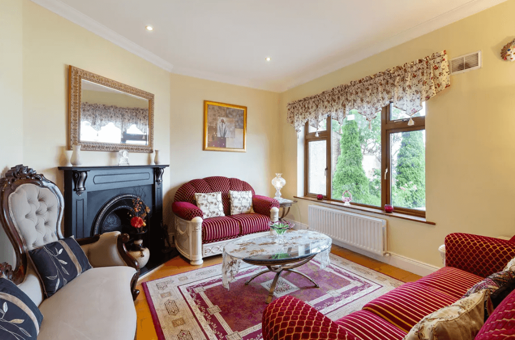 1 Leopardstown Rise Leopardstown Dublin 18 by George and Maguire Properties family room with large red rug on timber floor with fireplace, small sofas and large window with views to the front garden