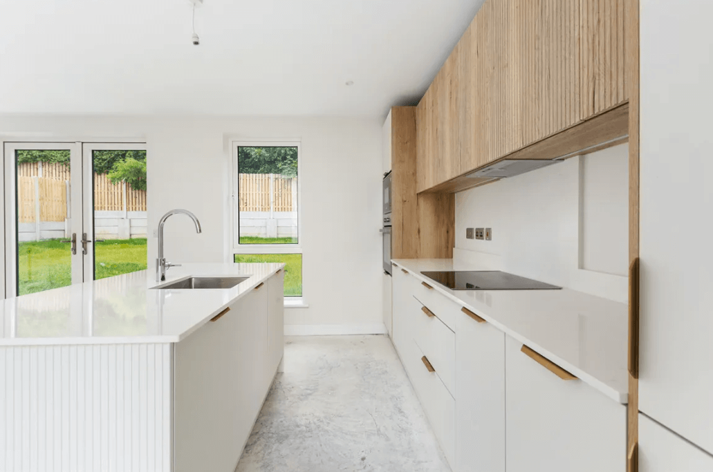 38 Glendarragh Altidore Newtownmountkennedy, Wicklow George and Maguire Properties for sale kitchen with white and timber-style cupboards, large white breakfast island with marble countertop and views to the rear garden