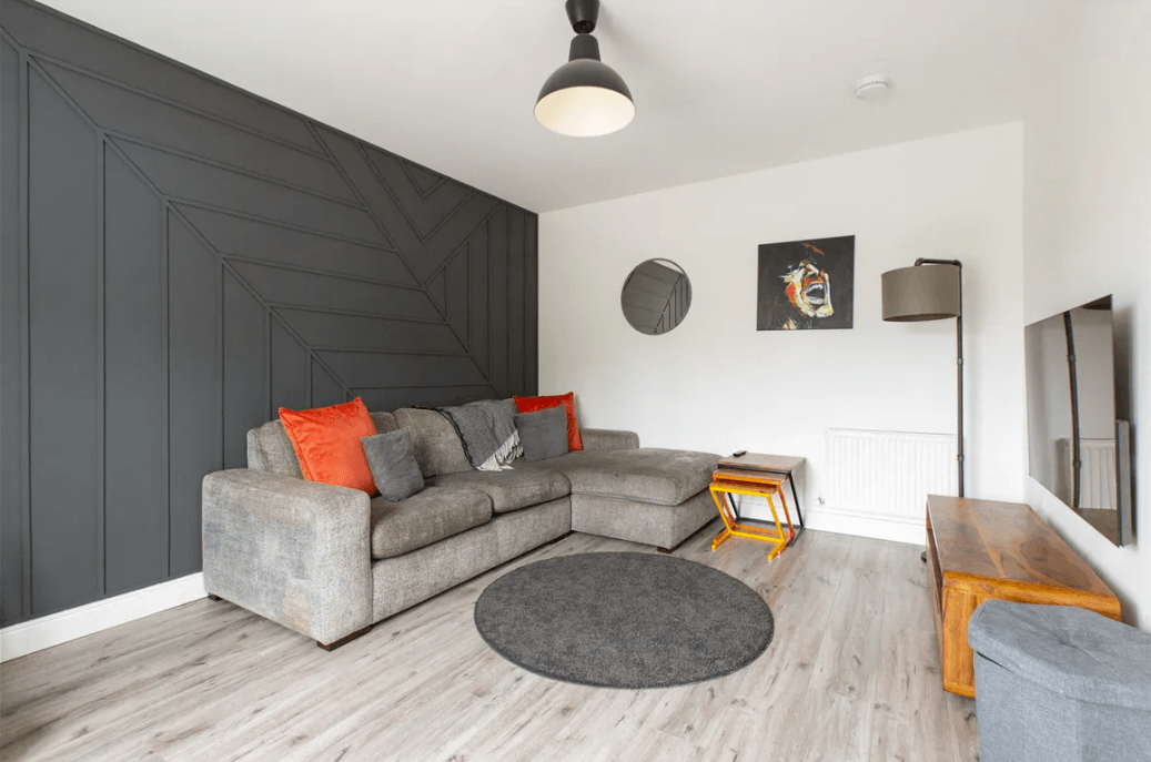 77 Monalin , Newtownmountkennedy, Wicklow George and Maguire Properties living room with grey timber-effect flooring, large grey sofa and a dark feature wall