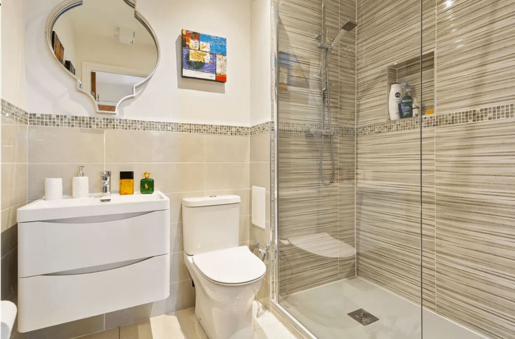 19 Rockbrae Hall Ticknock Hill Sandyford Dublin 18 George and Maguire Properties main bathroom with tiled shower with glass door, white toilet and sink on a tiled floor