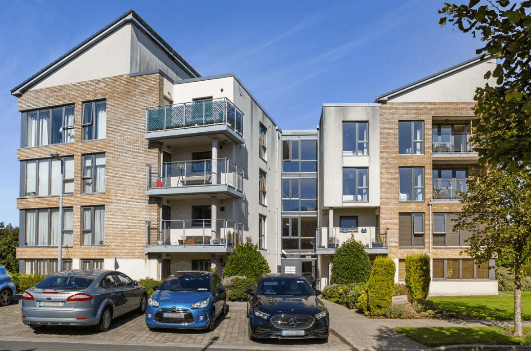 19 Rockbrae Hall Ticknock Hill Sandyford Dublin 18 George and Maguire Properties front view of the property apartment block with cars parked outside and some greenery