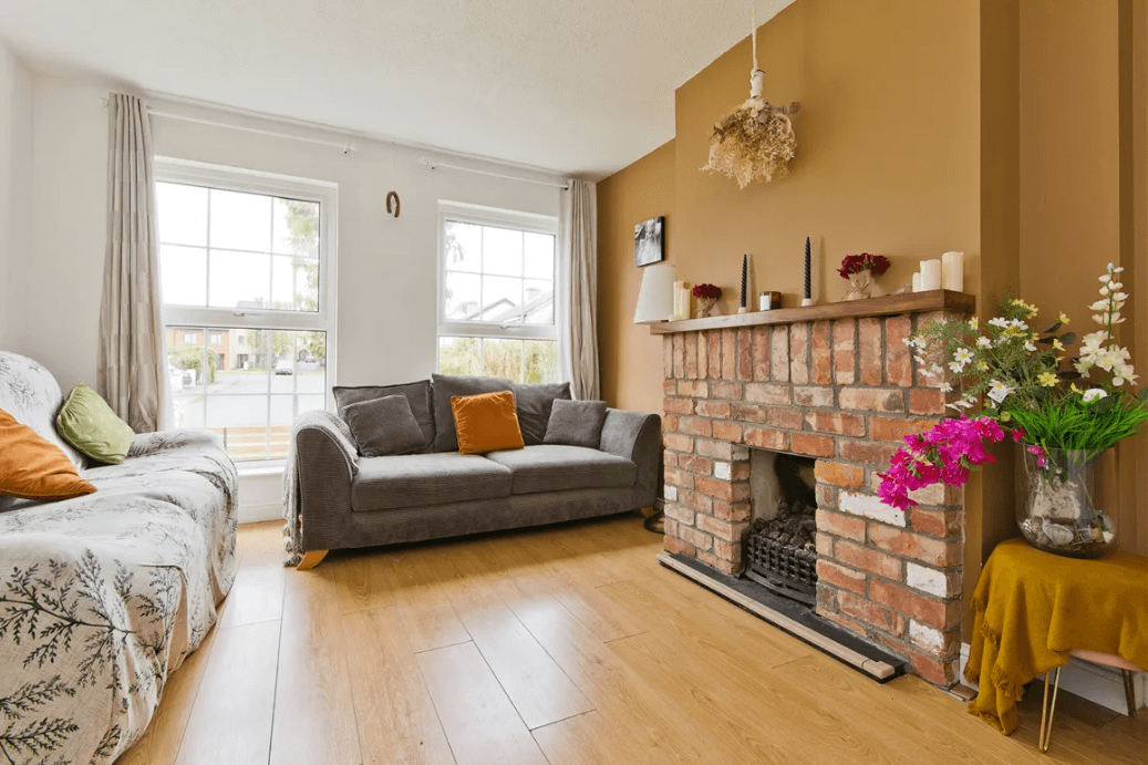 31 Herbert Bray Wicklow George and Maguire Properties living room with timber flooring, brick fireplace, large dark sofa and window with view to front garden